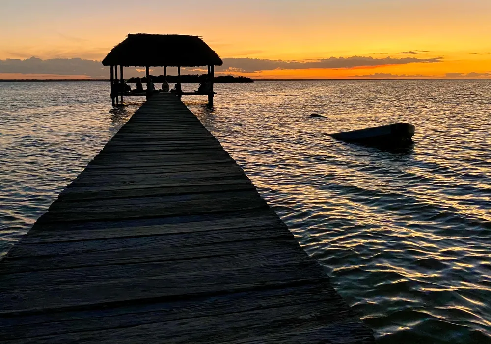 Holzsteg mit Pavillon im Meer bei Sonnenuntergang