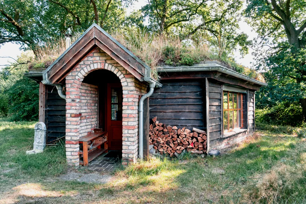 Kleines Haus aus Backstein und Holz mit bewachsenem Dach