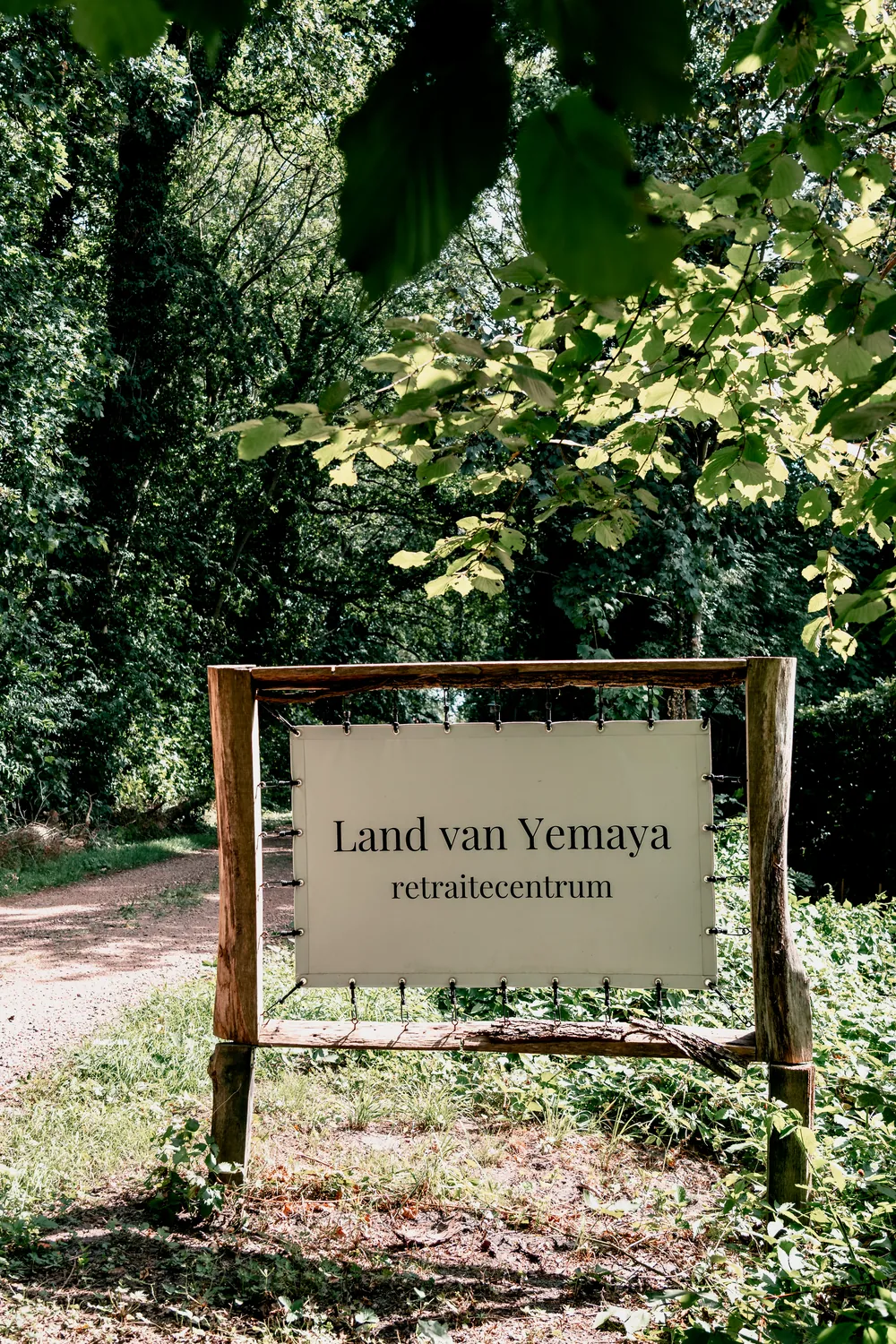 Holzschild am Waldweg mit der Aufschrift des Retreat-Zentrums