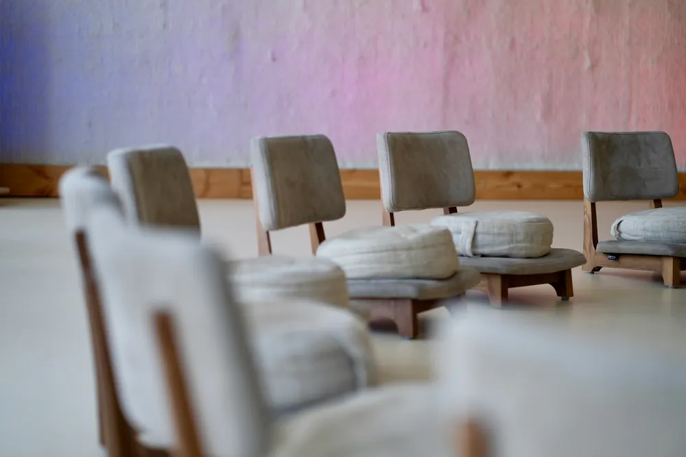 Leerer Seminarraum mit niedrigen Sesseln, auf der Wand liegt violettes Licht
